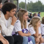 Een groep jonge Anderlecht-supporters met een volwassen begeleider op de tribune.