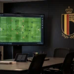 Lege videoanalysruimte met een Rode Duivels-embleem op een wandpaneel.