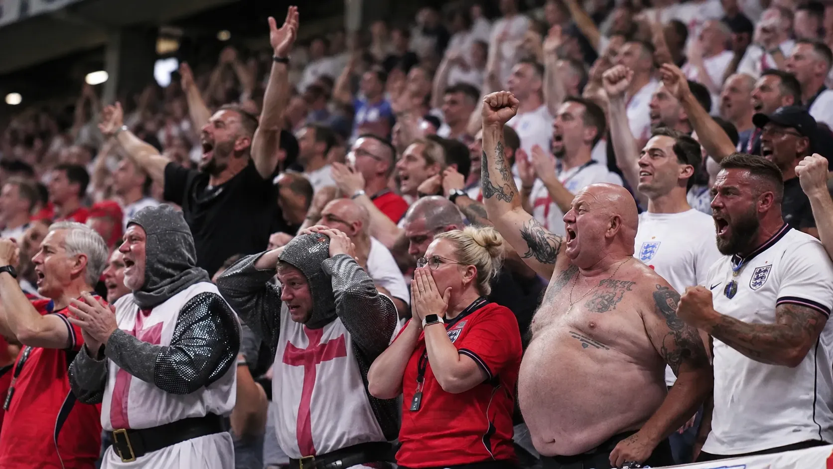 Een dicht opeengepakte groep Engelse voetbalsupporters op een volle tribune.