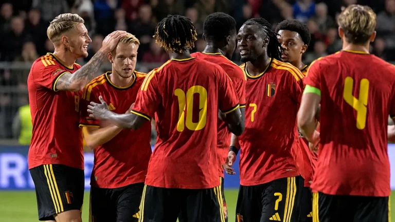 Een groep Belgische U21-spelers in rode wedstrijdtenues viert samen op het veld.