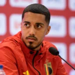 Youri Tielemans spreekt op een persconferentie in Rome in een rood Belgisch trainingsjack.