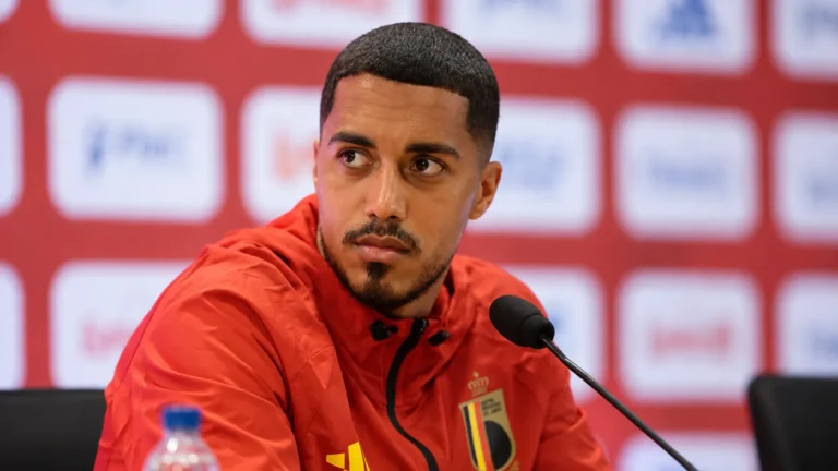 Youri Tielemans spreekt op een persconferentie in Rome in een rood Belgisch trainingsjack.