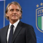 Roberto Mancini in donker pak in een Italiaanse voetbalmediaruimte.