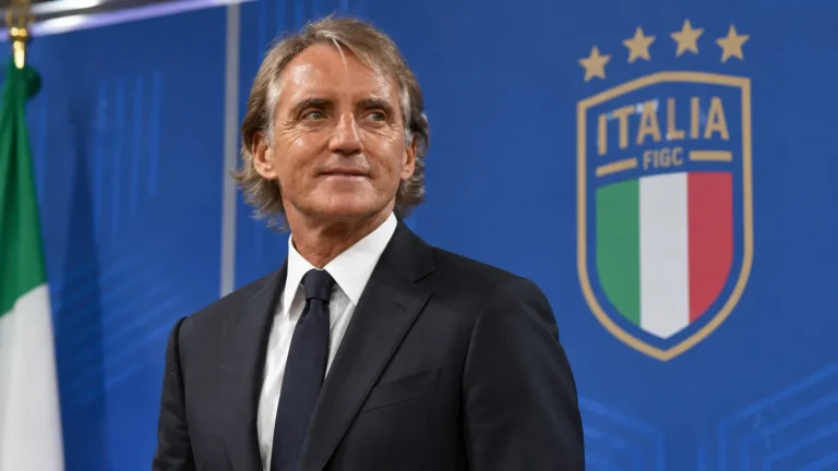 Roberto Mancini in donker pak in een Italiaanse voetbalmediaruimte.