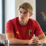 Charles De Ketelaere in het rode shirt van de Belgische nationale ploeg aan een interviewtafel.