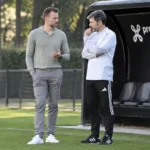 Twee medewerkers van de Belgische voetbalbond naast een trainingsveld.