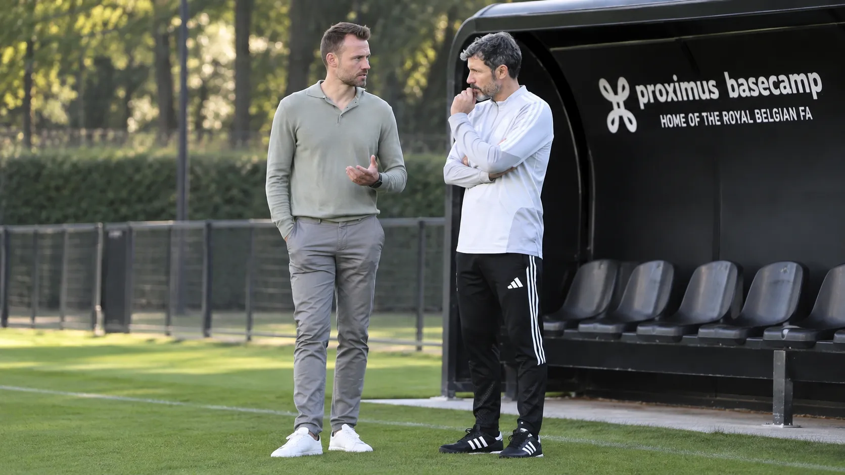 Twee medewerkers van de Belgische voetbalbond naast een trainingsveld.