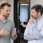 Twee niet-spelende voetbalmedewerkers in gesprek in een gang van de KBVB.