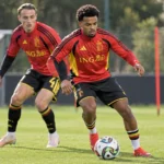 Twee voetballers in rode trainingskleding tijdens een oefensessie op het veld.