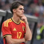 Charles De Ketelaere in het Belgische nationale ploegtenue aan de zijlijn van een voetbalveld.