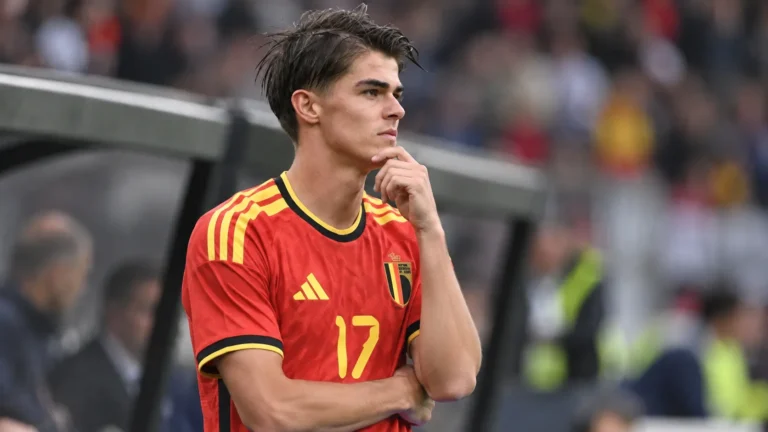 Charles De Ketelaere in het Belgische nationale ploegtenue aan de zijlijn van een voetbalveld.