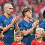 Een groep spelers van Royal Antwerp FC in blauwe wedstrijdshirts met jonge mascottes op het veld.