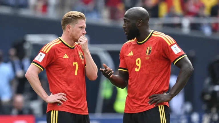 Twee ervaren Belgische internationals in rood tenue overleggen op het veld.