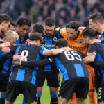 Een groep Club Brugge-spelers vormt vlak voor een wedstrijd een huddle op het veld.