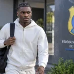 Jorthy Mokio arriveert in neutrale sportkleding bij een Congolees trainingscomplex.