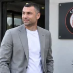 Burak Yilmaz voor het trainingscomplex van Çorum FK met het clubembleem bij de ingang.