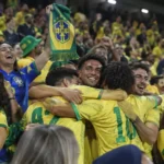 Een groep Braziliaanse supporters viert uitbundig in de tribune met een Braziliaanse sjaal.