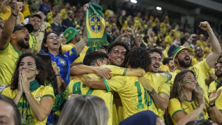 Een groep Braziliaanse supporters viert uitbundig in de tribune met een Braziliaanse sjaal.
