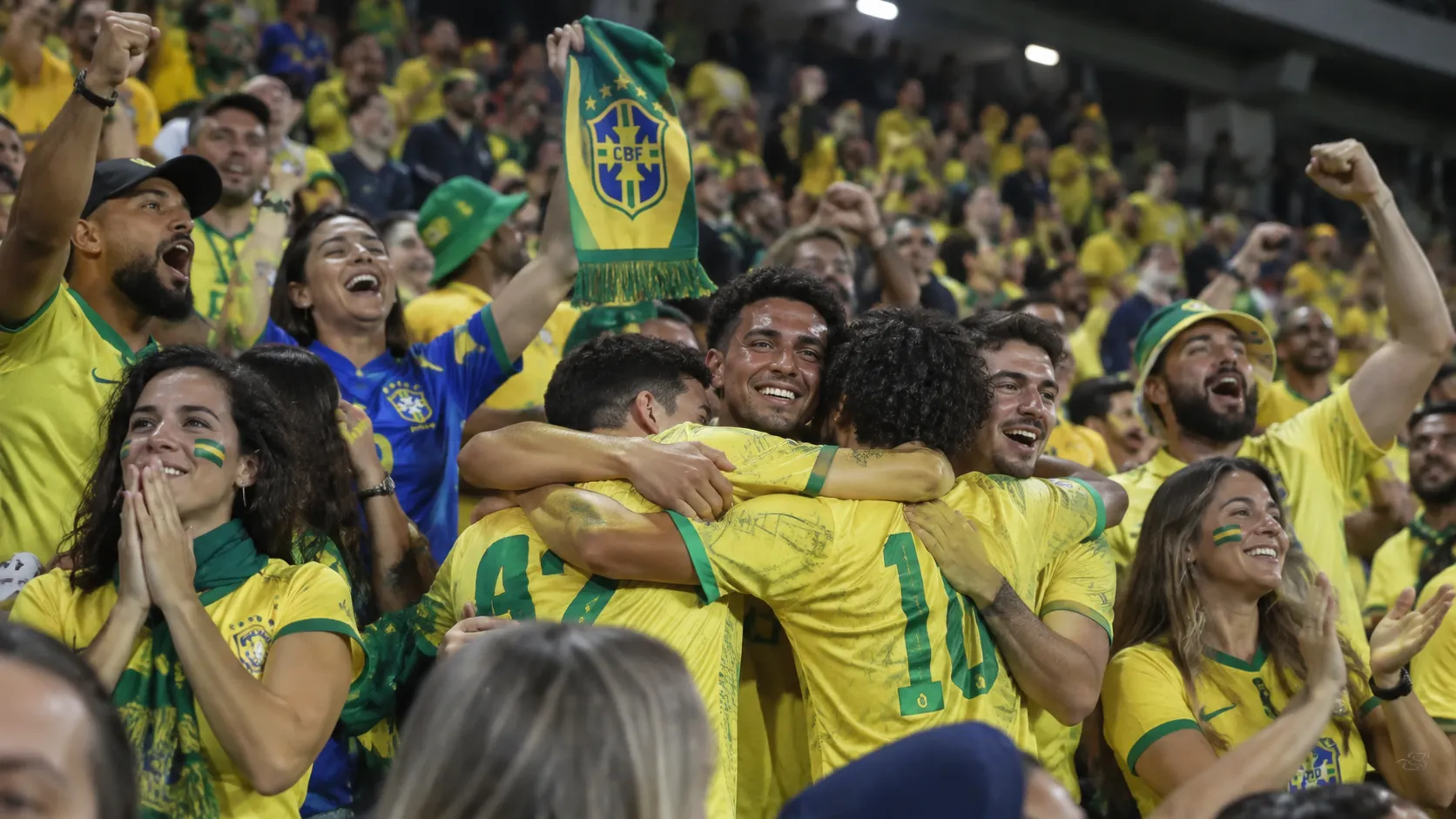 Een groep Braziliaanse supporters viert uitbundig in de tribune met een Braziliaanse sjaal.