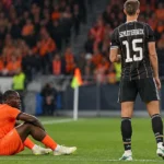 Twee voetballers in hun brongebonden wedstrijdtenues tijdens een nieuw Nations League-moment.