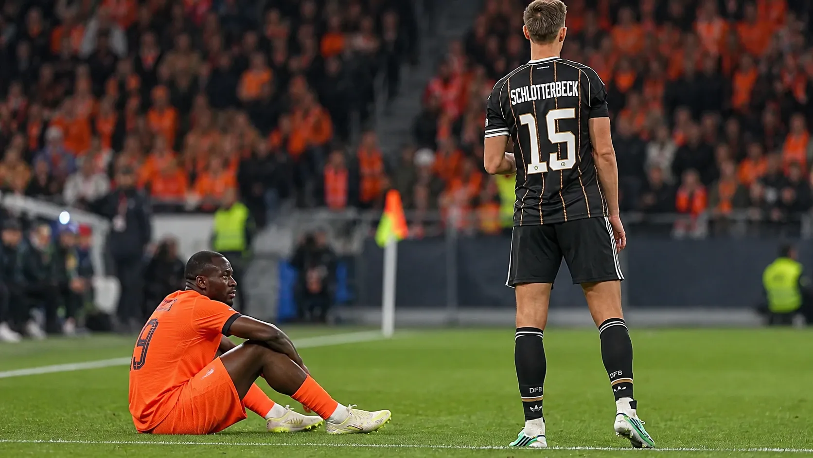 Twee voetballers in hun brongebonden wedstrijdtenues tijdens een nieuw Nations League-moment.
