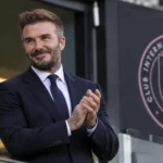 David Beckham in een donker pak in een voetbalstadion van Inter Miami.