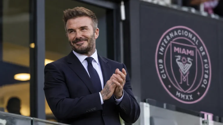 David Beckham in een donker pak in een voetbalstadion van Inter Miami.