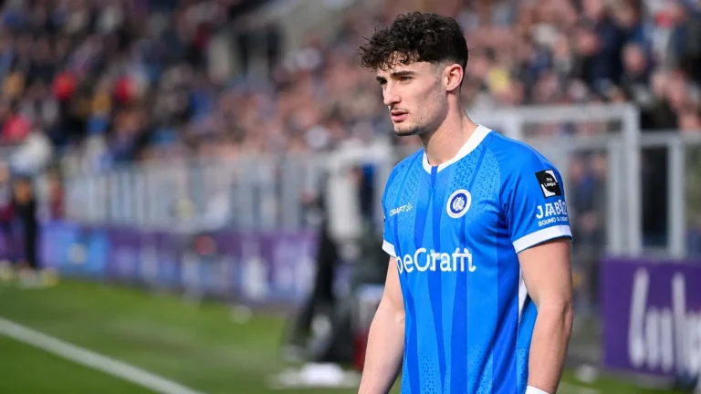 Robin Mirisola in het tenue van KRC Genk langs de zijlijn van een voetbalveld.