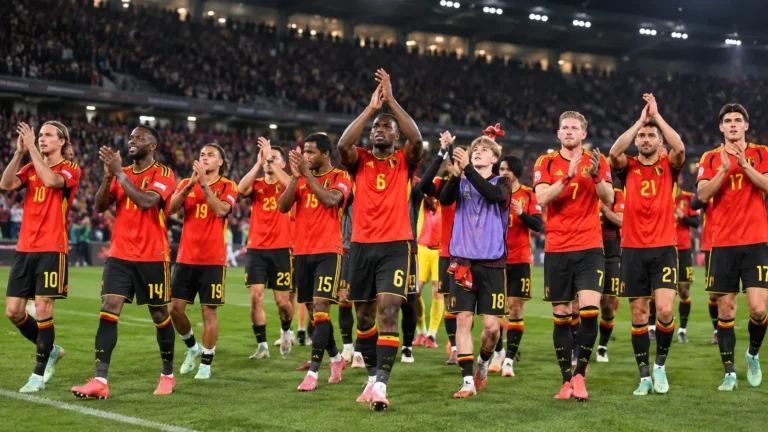 Belgische spelers applaudisseren na afloop op het veld van een verlicht stadion.