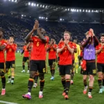 Belgische spelers in rode nationale tenues applaudisseren na een wedstrijd in het stadion.