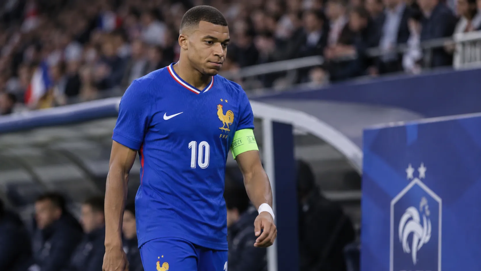 Kylian Mbappé in het tenue van Frankrijk terwijl hij naar de zijlijn wandelt.