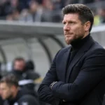 Sébastien Pocognoli staat met gekruiste armen langs de zijlijn van een stadion.