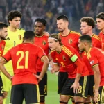 Een groep Belgische spelers in rode nationale tenues op het veld tijdens een wedstrijdmoment.