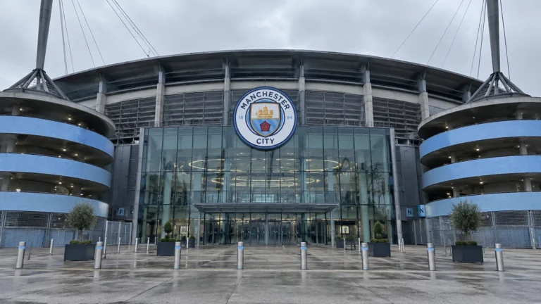 Lege ingang van het Etihad Stadium met een Manchester City-embleem op de gevel.