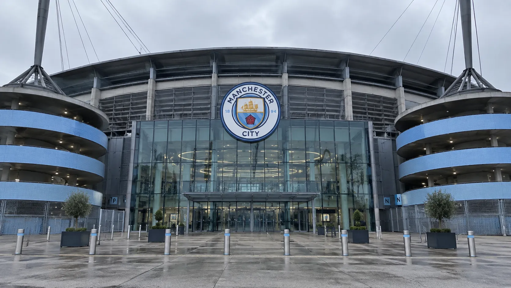 Lege ingang van het Etihad Stadium met een Manchester City-embleem op de gevel.