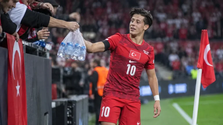 Arda Güler in het Turkse nationale tenue terwijl hij bij een hoekschop een zak water aanneemt.