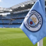 Een lichtblauwe hoekvlag met het embleem van Manchester City langs het veld.