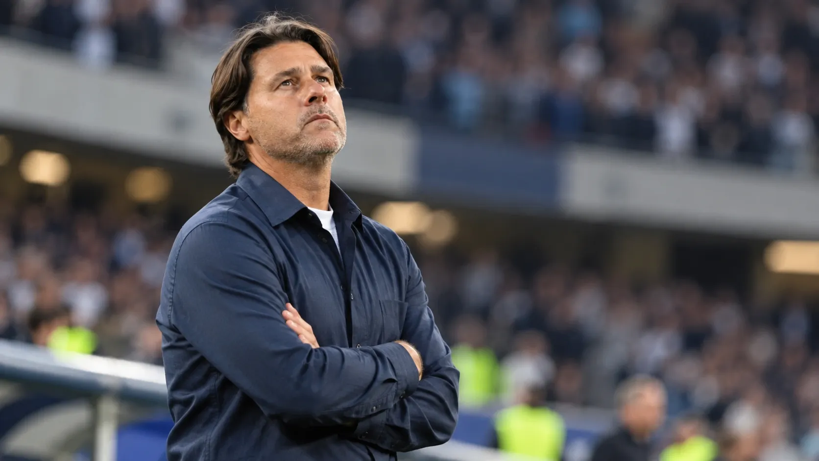 Mauricio Pochettino kijkt peinzend omhoog langs de zijlijn van een stadion.