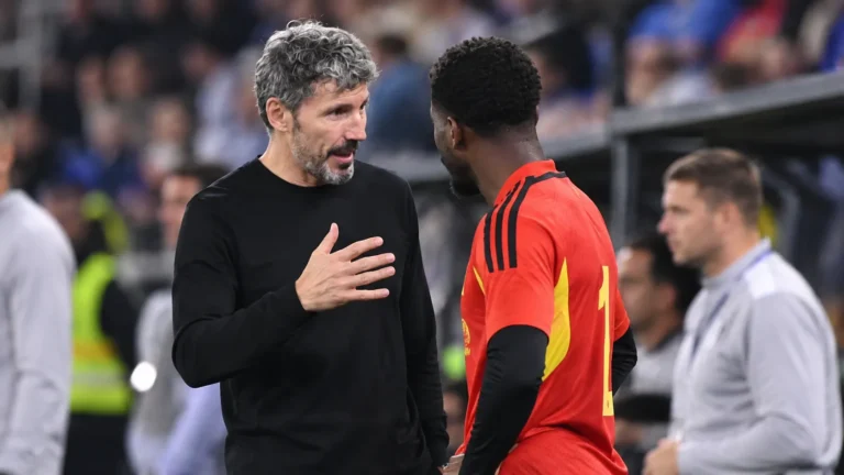 Mark van Bommel in zwarte kledij bij Belgische spelers langs het veld.