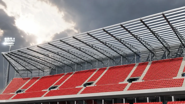 Lege tribune met rode zitjes onder de stalen dakconstructie van een stadion.