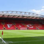 Lege rode tribunes van het stadion van Liverpool met het clubopschrift in de zitplaatsen.