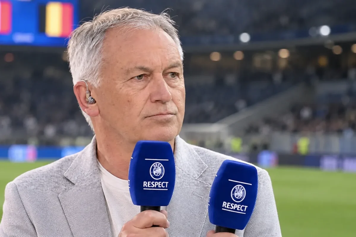 Marc Degryse spreekt als analist met een microfoon in een stadionomgeving.