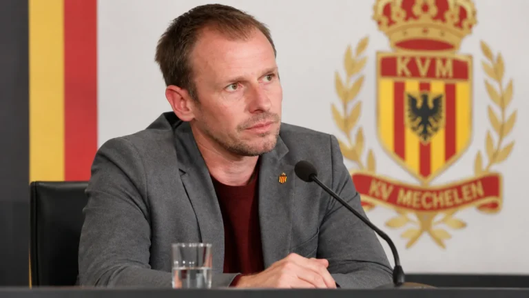Tom Caluwé zit aan een persmicrofoon tijdens een bijeenkomst van KV Mechelen.