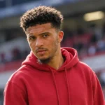 Jadon Sancho in neutrale vrijetijdskleding in een spelerszone van een voetbalstadion.