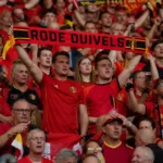 Een collectieve groep supporters van de Rode Duivels met rode sjaals op de tribune.