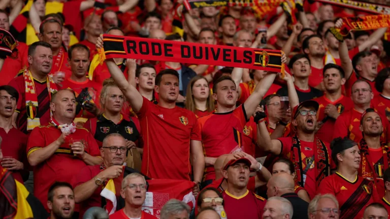 Een collectieve groep supporters van de Rode Duivels met rode sjaals op de tribune.