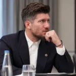 Sébastien Pocognoli in donker pak aan een vergadertafel.