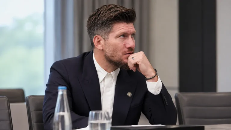 Sébastien Pocognoli in donker pak aan een vergadertafel.