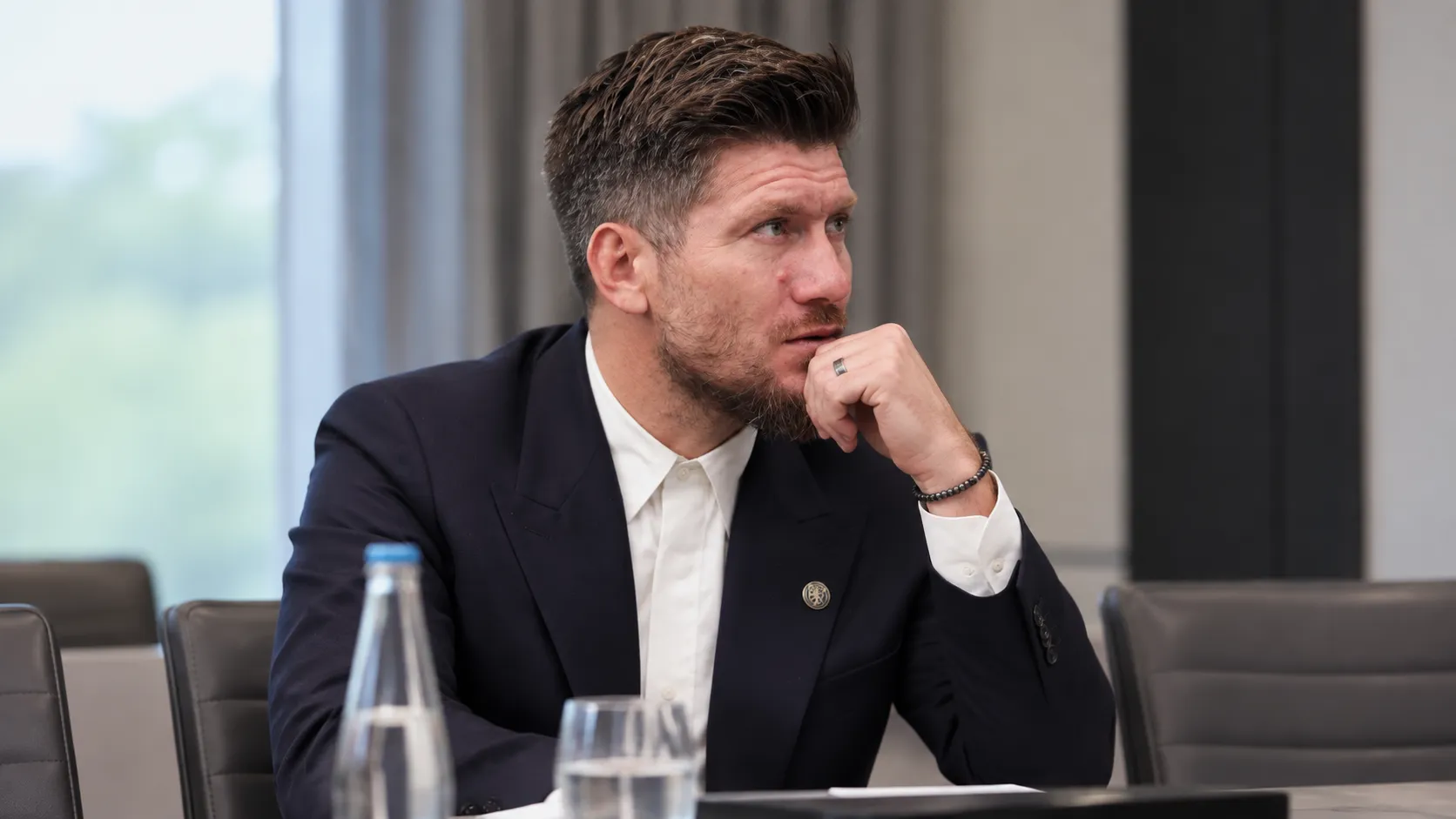 Sébastien Pocognoli in donker pak aan een vergadertafel.