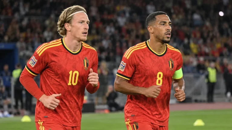 Twee Belgische spelers in rode nationale tenues tijdens de opwarming in het stadion.